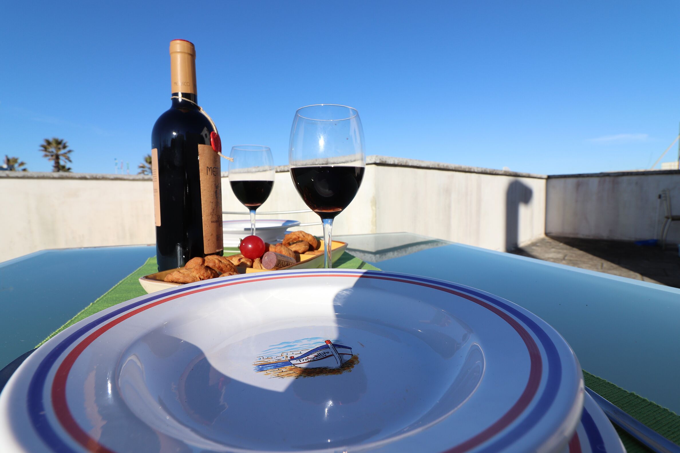 Een tafel met een fles wijn, twee glazen en een bord met eten.