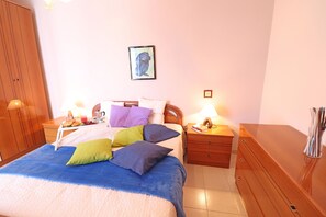 Quarto com cama, mesas de cabeceira, cômoda e um quadro na parede.