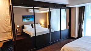 Ein Hotelzimmer mit Bett, Nachttisch, Lampe, einem Gemälde und einer Schiebetür.