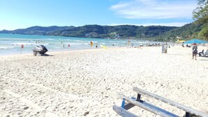A sandy beach with a jet ski, beach umbrellas, and a lifeguard flag. - 3008 - Luxurious Ocean View 1BR Apartment in Muang Pattaya, Thailand (Muang Pattaya)