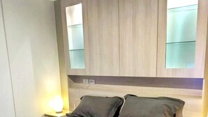 A modern bedroom with a bed, bedside lamps, and built-in cabinets. - 3237 - Luxurious City View Studio Condo in Muang Pattaya with Pool Access (Muang Pattaya)