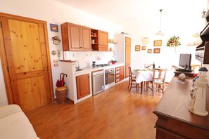 Una cucina con mobili in legno, un tavolo da pranzo, sedie e un frigorifero.