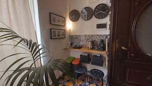 Una cocina pequeña con una cafetera, una repisa con utensilios de cocina y una puerta.