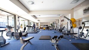 A gym with cardio machines, free weights, and exercise balls.