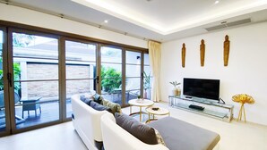 Een moderne woonkamer met een bank, een televisie en een glazen salontafel.