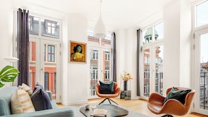 Ein geräumiges Wohnzimmer mit einer Couch, zwei Sesseln, einem Couchtisch und einem Bild an der Wand.