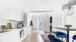 Una cocina moderna con armarios blancos, un microondas y un comedor con sillas azules.