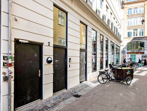 Un immeuble avec une rangée de portes noires, un vélo garé devant et une rue pavée.