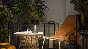 Un rincón interior acogedor con una mesa redonda, una silla y una planta en maceta.