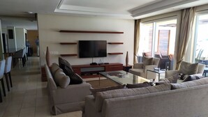 Ein modernes Wohnzimmer mit Flachbildfernseher, Sofas, einem Couchtisch und einem Essbereich mit Stühlen und Tisch.