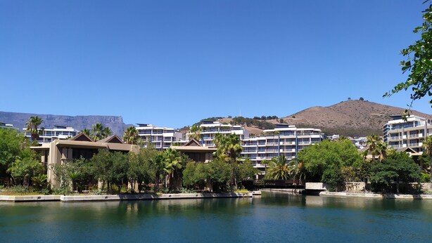 Ein Resort mit mehreren Gebäuden, einem Gewässer und einer hügeligen Landschaft im Hintergrund.