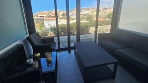 Un balcon donnant sur un quartier résidentiel, une table en osier avec une bougie et un canapé.