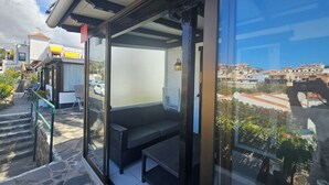 Un balcon avec un canapé et une table, un escalier en pierre et une vue sur les bâtiments environnants.