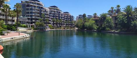 A waterfront hotel with multiple balconies, a dock, and lush greenery.