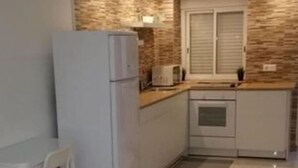 Eine moderne Küche mit Kühlschrank, einem Esstisch mit Stuhl und einem Fenster mit Jalousien.