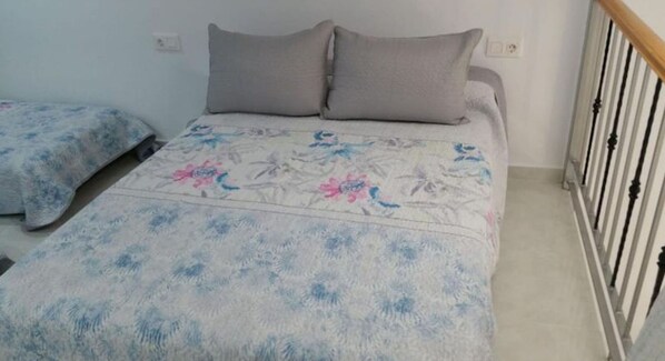 A bedroom with a bed, two pillows, and a nightstand.