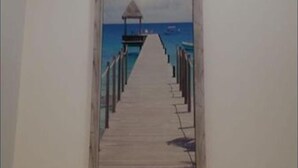Eine Holzstege führt zu einem kleinen Gebäude am Meer.