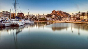 Un port de plaisance avec des bateaux, une montagne imposante en arrière-plan et un hôtel appelé « METRO ALICANTE » sur la droite.
