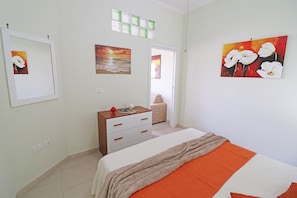 Quarto com cama, penteadeira e obras de arte nas paredes.