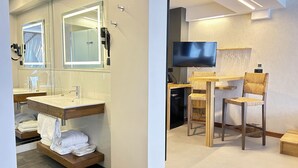 Une salle de bain moderne dotée d’un grand miroir, de deux vasques et d’un téléviseur à écran plat.
