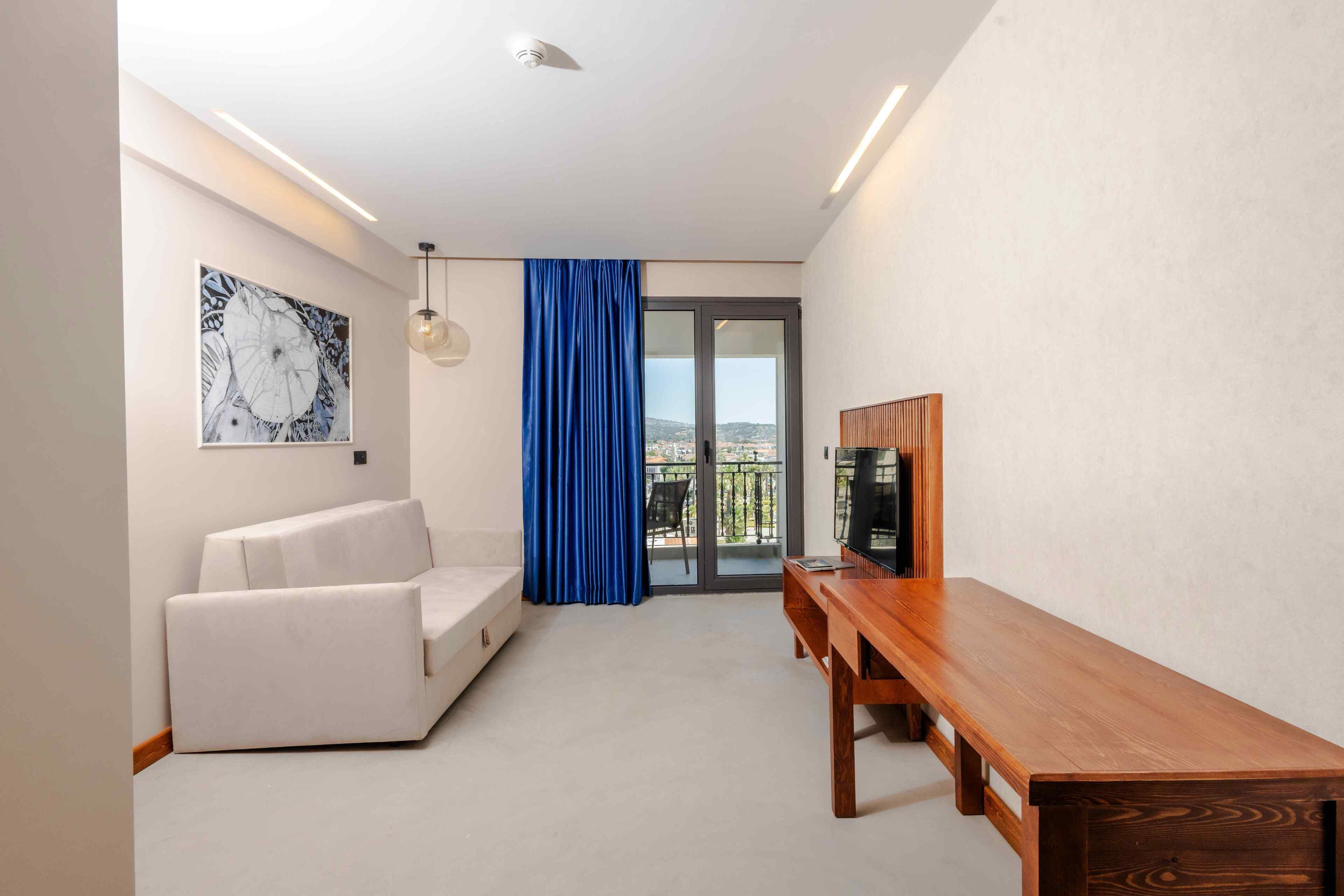 Un salón moderno con un sofá blanco, una mesa de comedor de madera y un ventanal con vistas.