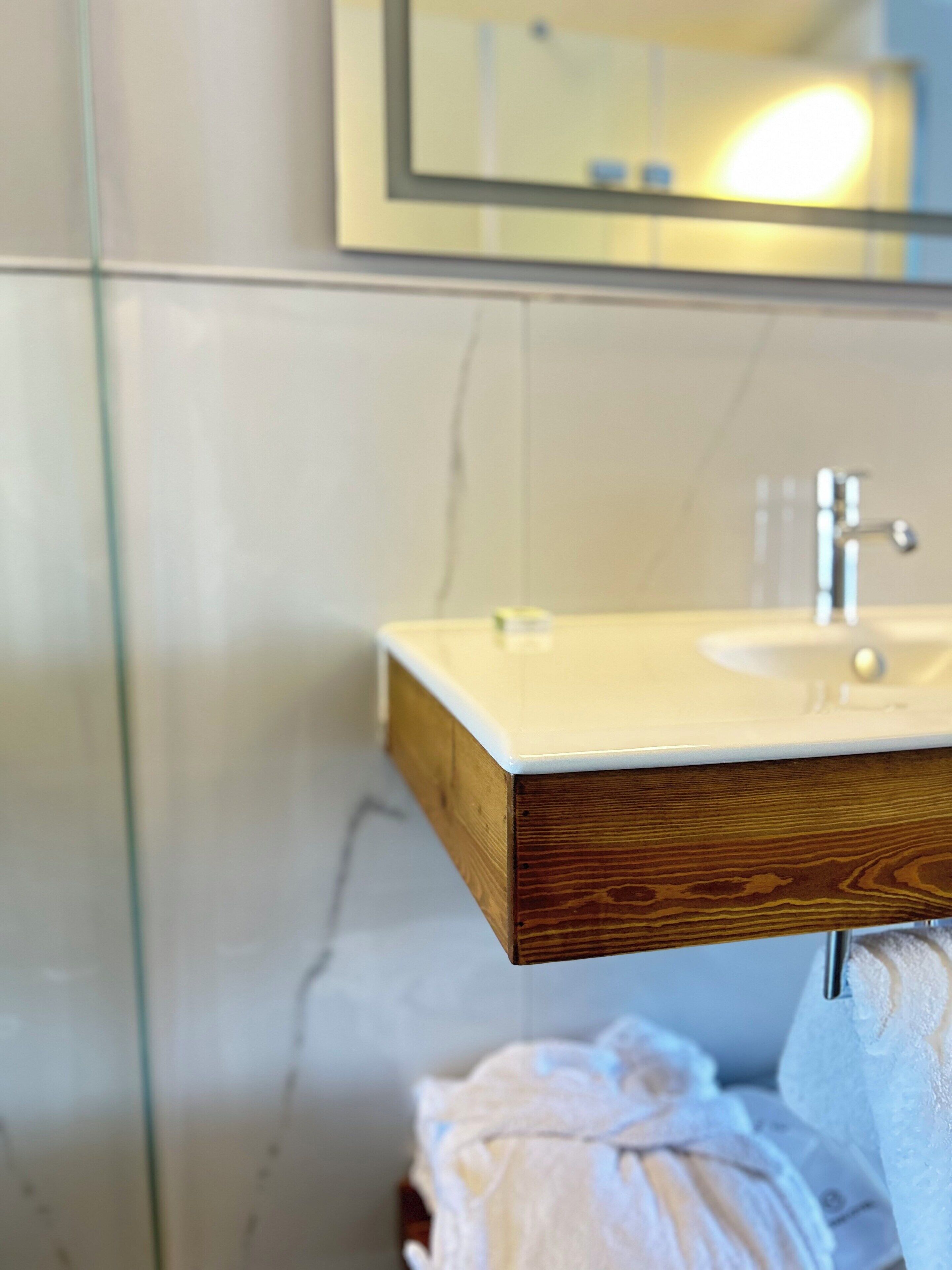 Une salle de bain avec un meuble-lavabo en bois, un miroir et un porte-serviettes.