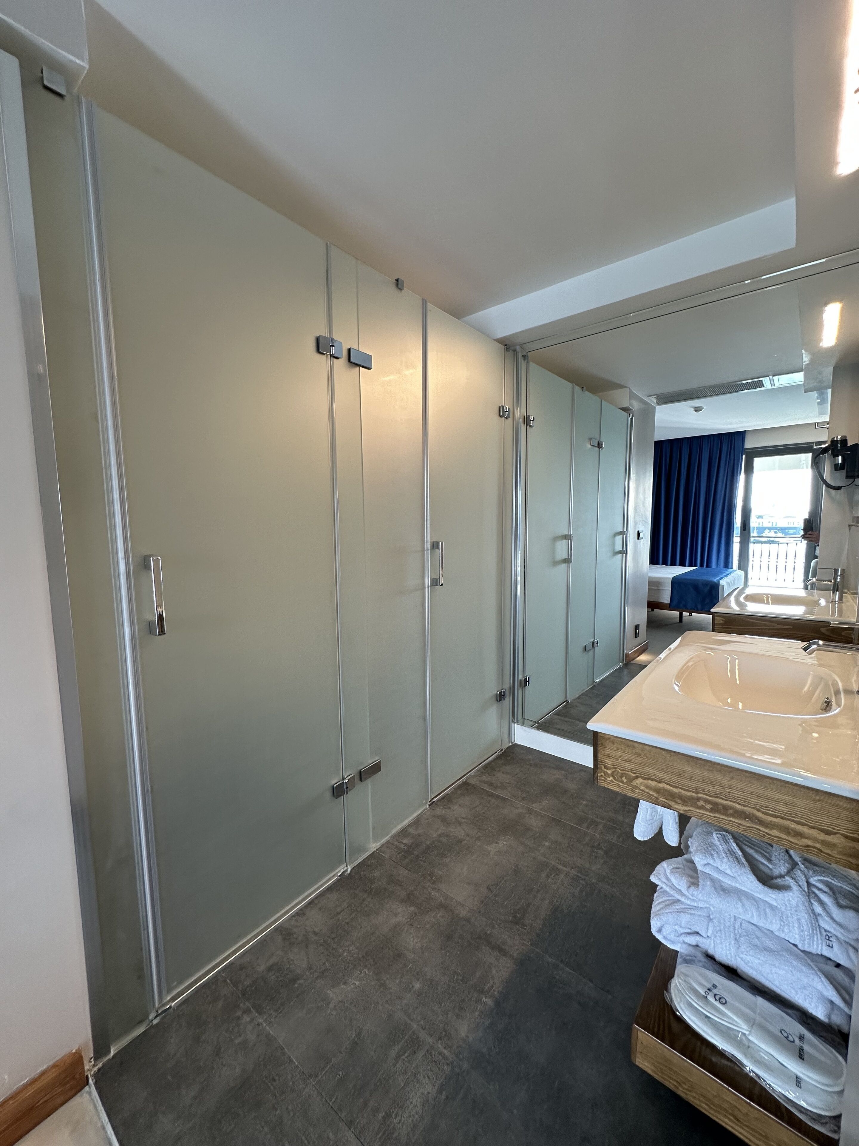 A modern hotel bathroom with a large mirror, a bathtub, and a walk-in shower.