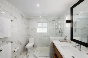 A modern bathroom with a toilet, shower, and sink.
