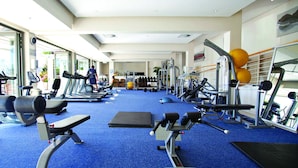 Une salle de sport équipée de tapis de course, d’appareils de musculation et de ballons d’exercice.