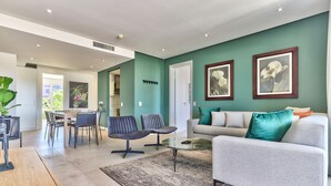 Un salon moderne avec un canapé gris, une table basse et un coin repas comprenant des chaises et une table.