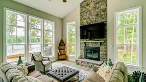 A living room with a stone fireplace, large windows, and a cozy seating area.