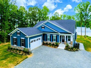 A two-story house with a blue exterior, a front porch, and a driveway leading to the garage.