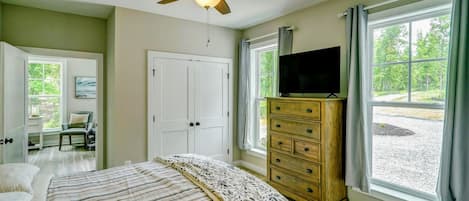 A bedroom with a bed, a dresser, a ceiling fan, and a TV.