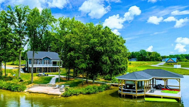 A lakeside house with a dock and a covered boat launch area.