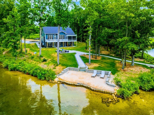 Una casa con un muelle que se adentra en un lago, rodeada de abundante vegetación.