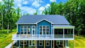 A two-story house with a balcony, large windows, and a covered porch.