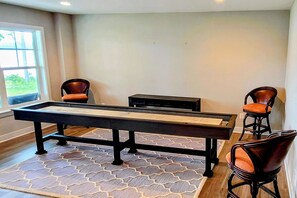 A pool table with two chairs, a bench, and a patterned rug in a room with a window.