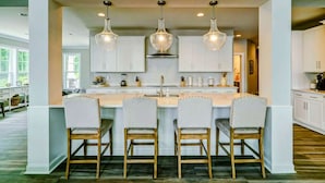 A modern kitchen with a central island, white cabinetry, and pendant lighting.