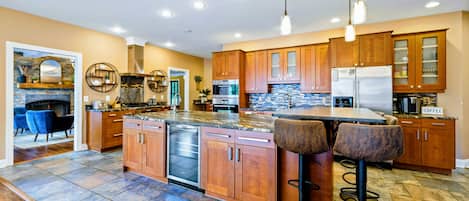 A modern kitchen with wooden cabinets, a built-in dishwasher, and a central island with bar stools.