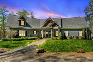 A two-story house with a front porch, a driveway, and a well-maintained lawn. - Huge 8BR Lakefront Lake Anna, Beach, Dock, Hot Tub (Bumpass)