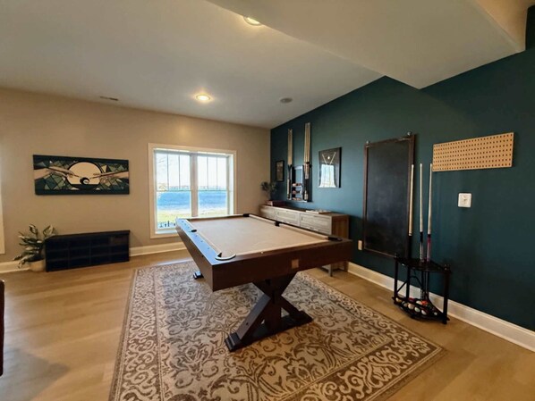 A pool table in a room with a view of the outdoors through a large window. - Huge 8BR Lakefront Lake Anna, Beach, Dock, Hot Tub (Bumpass)