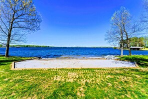 A grassy area with a concrete patio, trees, and a body of water. - Huge 8BR Lakefront Lake Anna, Beach, Dock, Hot Tub (Bumpass)