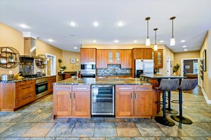 A spacious kitchen with wooden cabinets, a central island, and a stainless steel refrigerator. - Huge 8BR Lakefront Lake Anna, Beach, Dock, Hot Tub (Bumpass)