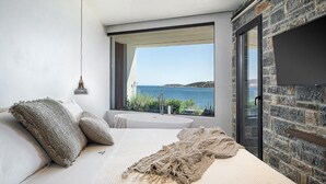 Quarto com uma janela grande, cama, banheira e parede de pedra.