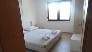 A bedroom with a bed, a bedside table, a window, and a small bathroom area. - Ilsad apartments - Apartment with pool 80 meters from sea - Great location (Ždrelac)