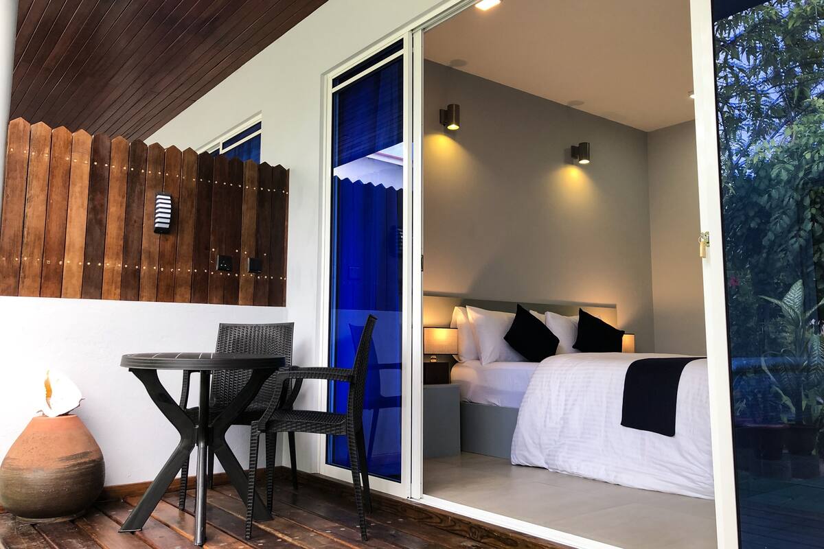 Een slaapkamer met een bed, nachtlampjes en uitzicht op de omgeving.