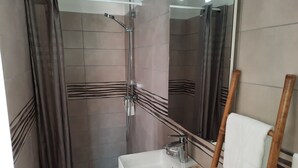 A bathroom with a shower, a sink, and a mirror.