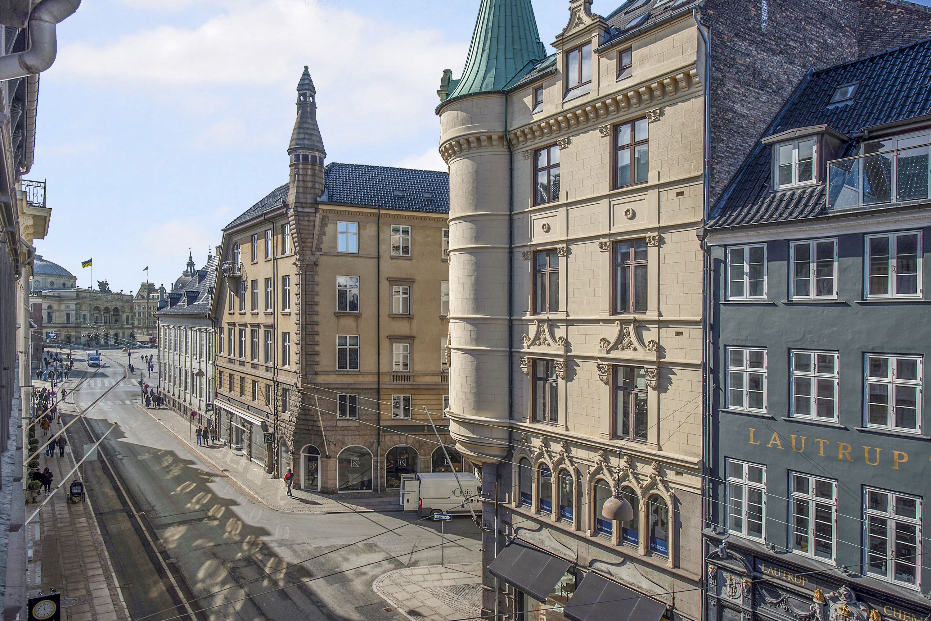 A street view with historic buildings, including a building with 'LAUTRUP' signage.