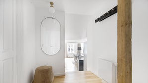 A hallway with a wooden floor, a round mirror, a small stool, and a radiator. - Regent 3 - Popular 3-Bdr Apt with Balcony in Centre (København)