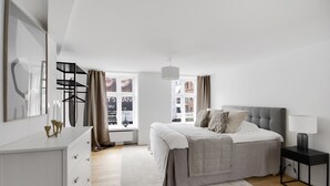 A modern bedroom with a bed, bedside table, and a dresser. - Regent 3 - Popular 3-Bdr Apt with Balcony in Centre (København)